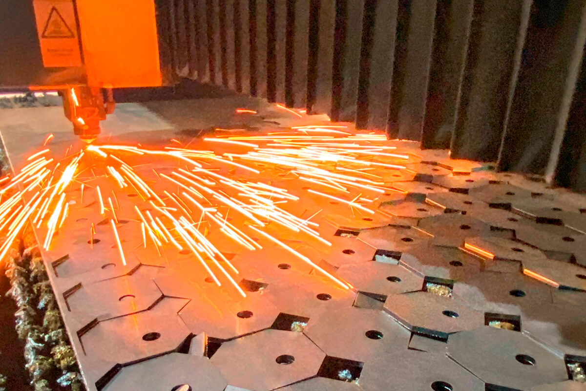 Serviço de corte a laser em chapa de aço com faíscas durante a operação